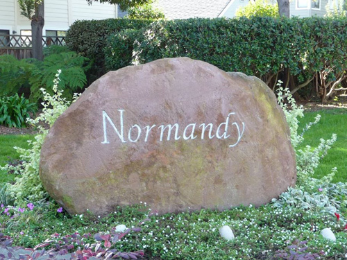 Exterior shot of Normandy Homeowners Association showing a large rock with the word Normandy engraved.