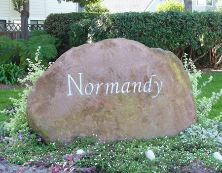 Exterior shot of Normandy Homeowners Association showing a large rock with the word Normandy engraved.